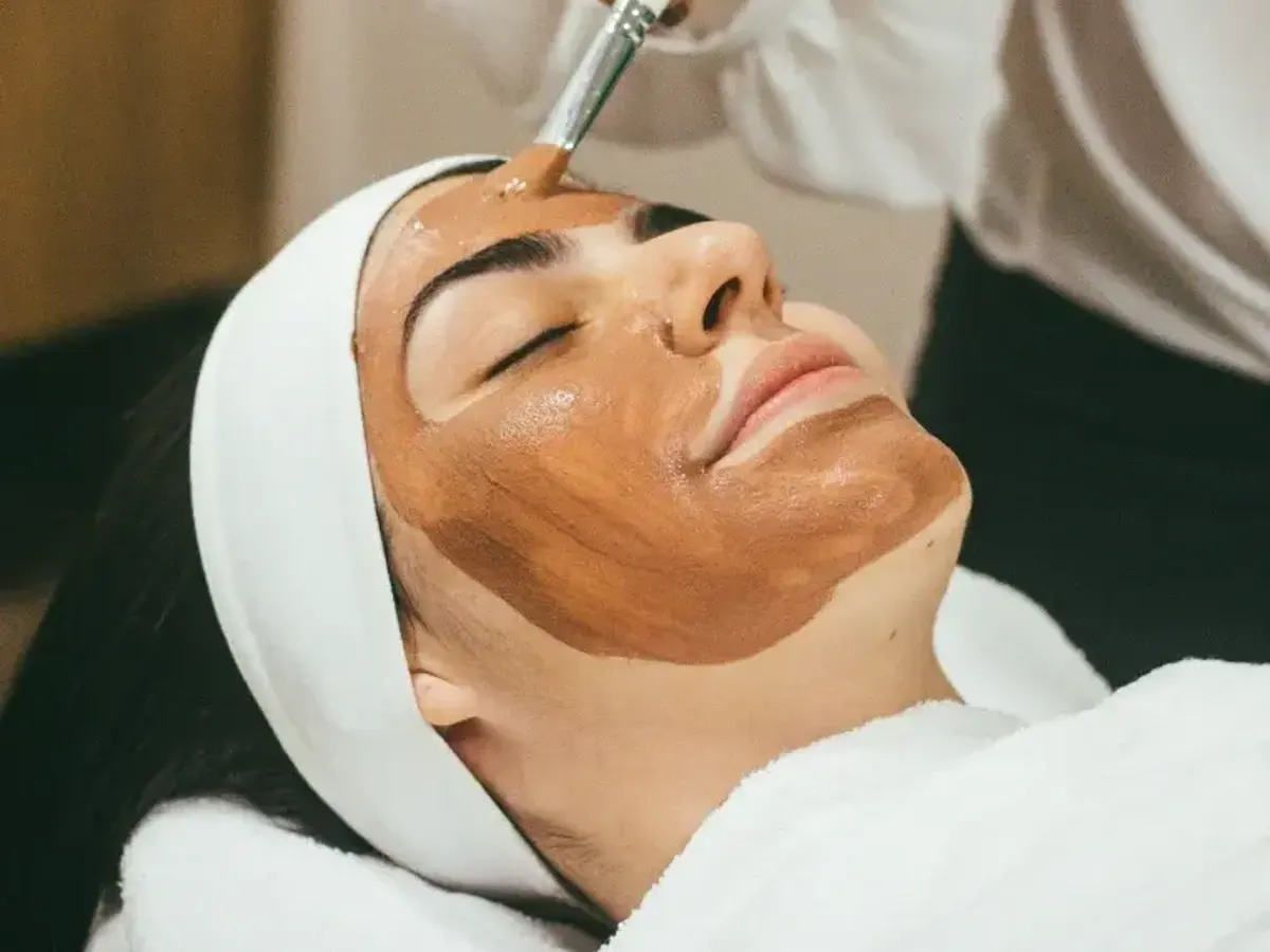 Facial product applied with a brush to a client lying down
